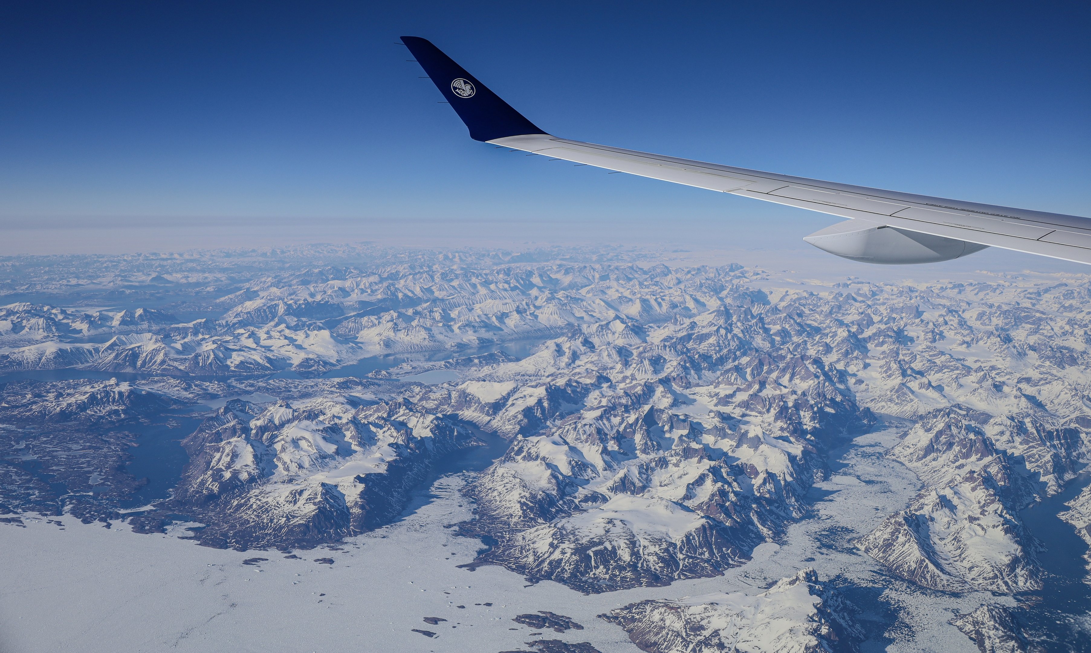 Scenic mountain landscape viewed from an airplane, highlighting rugged peaks and expansive valleys below.